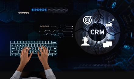 Hands typing on illuminated keyboard with CRM system interface showing customer support, sales growth, and marketing automation icons.