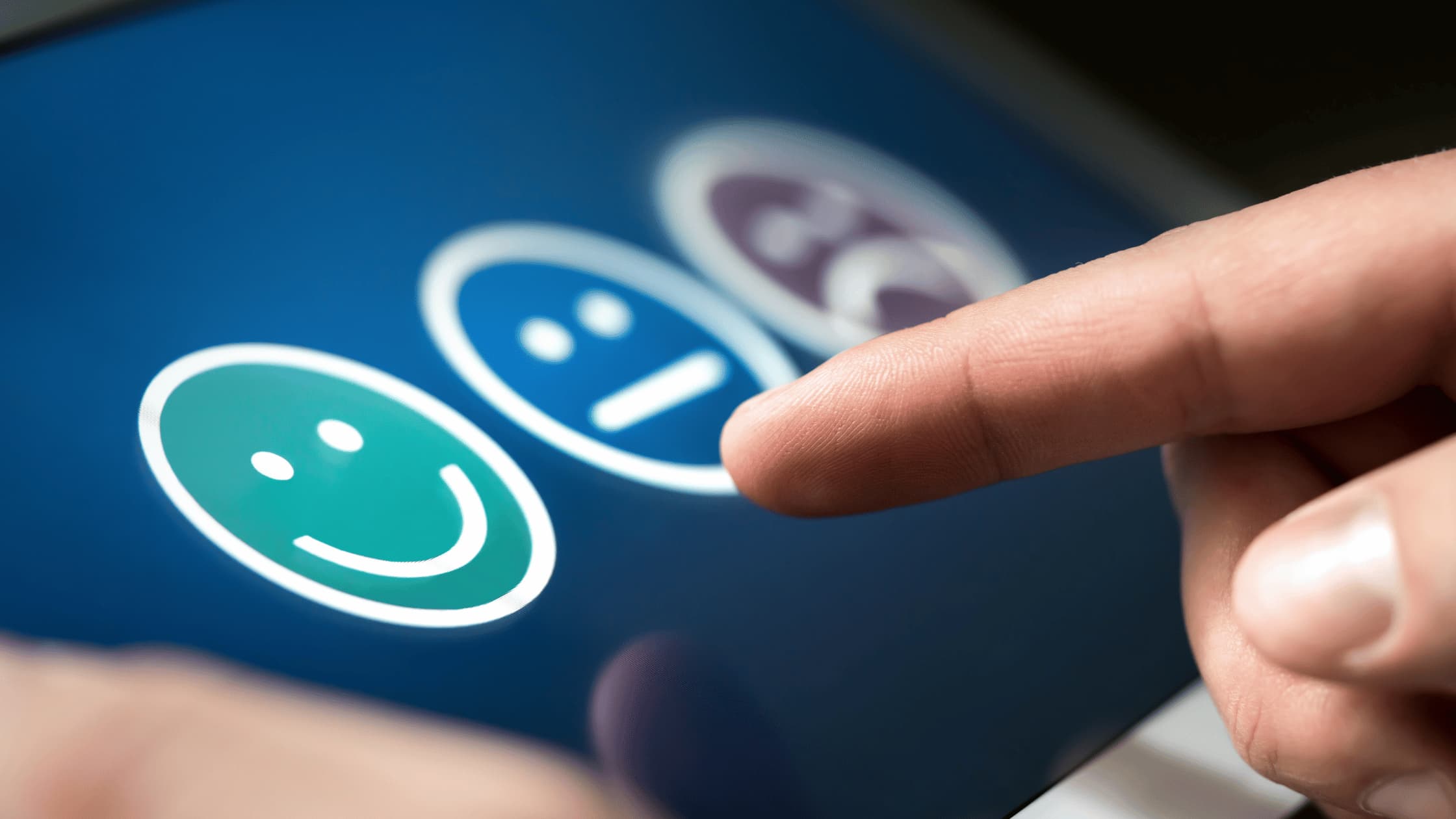 Customer feedback survey on touchscreen with finger selecting happy face emoji