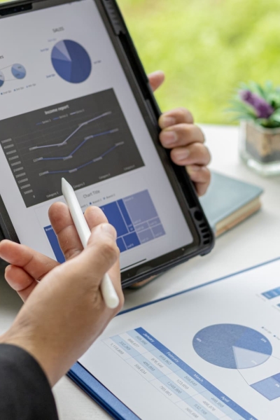 Business professional reviewing sales dashboard and performance analytics on tablet and reports.