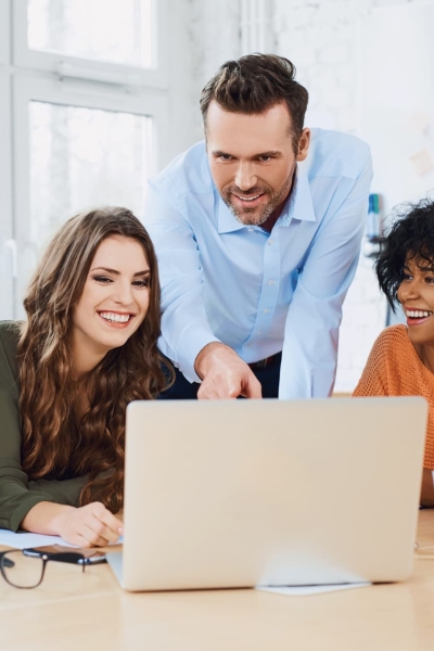 Digital marketing team collaborating on CRM software strategy around a laptop in a modern office.